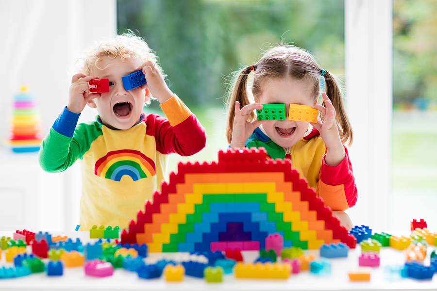 Two children playing joyfully with colourful blocks